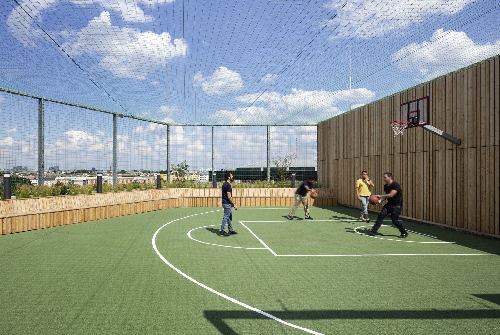 Zalando: Rooftop sports court with a basketball hoop, net enclosure and city view