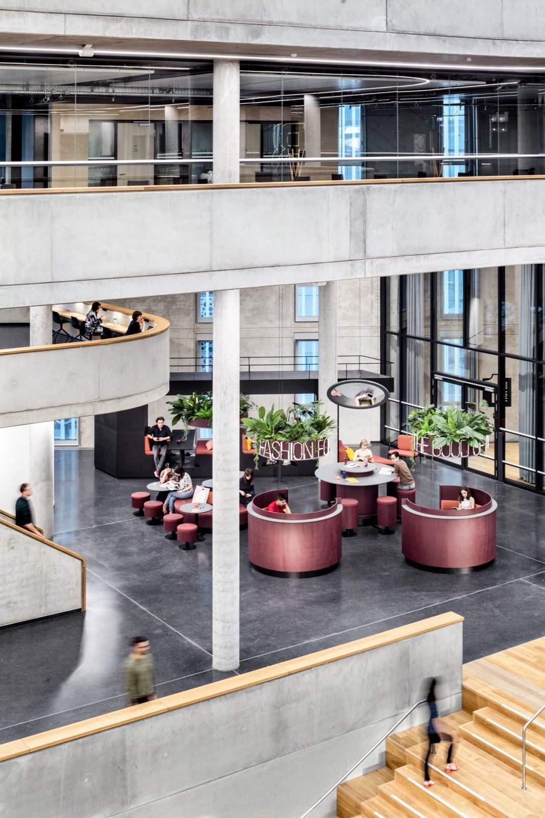 Zalando: Seating area with plants and round tables seen from a staircase