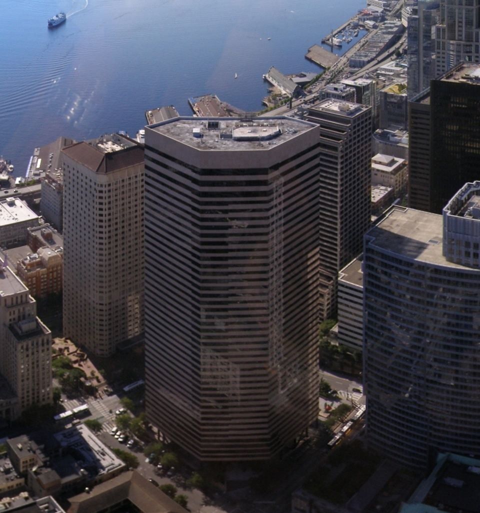 Dark high-rise office tower among downtown skyscrapers seen from above