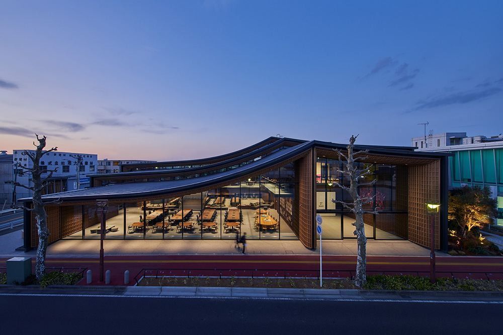 ZOZO: Building with a curved roof glowing from inside at dusk