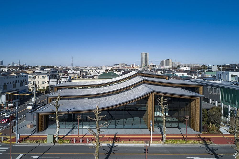 ZOZO: Elevated view of a building with three wavy roof layers among low-rise houses