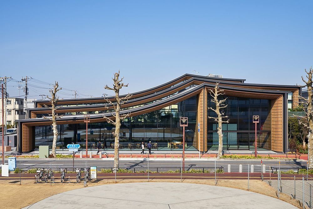 ZOZO: Front of a long building with layered wavy roofs and bare trees along the pavement