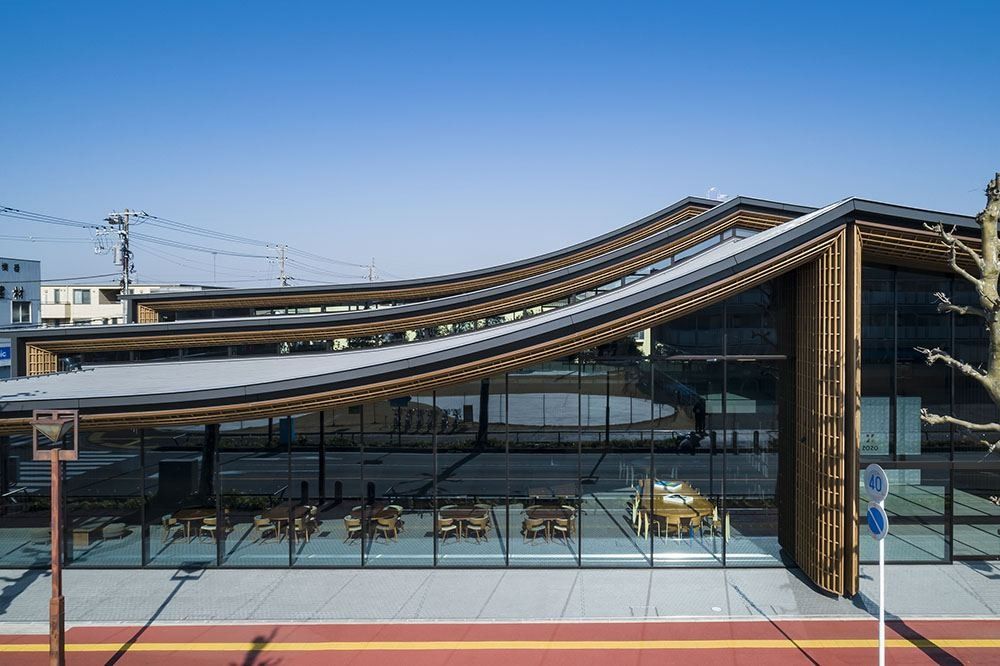 ZOZO: Glass facade under a sweeping roof that dips toward the street
