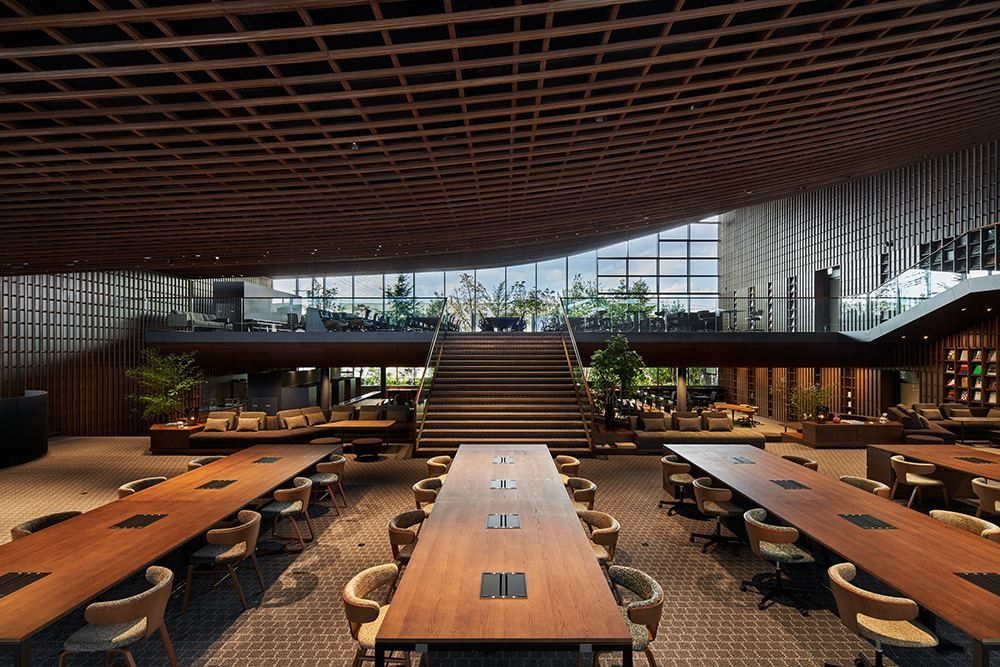 ZOZO: Long wooden tables with chairs facing a wide staircase and a raised lounge