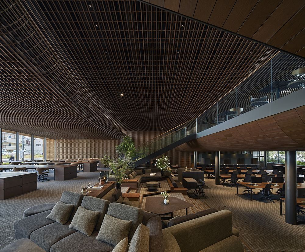 ZOZO: Lounge with grey sofas beneath a high wooden lattice ceiling and a glass balustrade