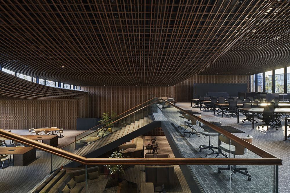 ZOZO: Open office with desks around a stair opening under a wooden lattice ceiling