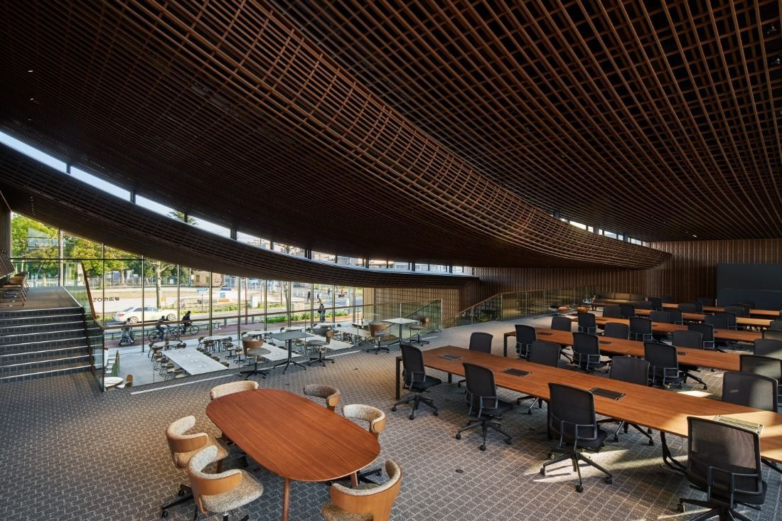 ZOZO: Oval meeting table and rows of desks on a lower level beside steps and tall windows