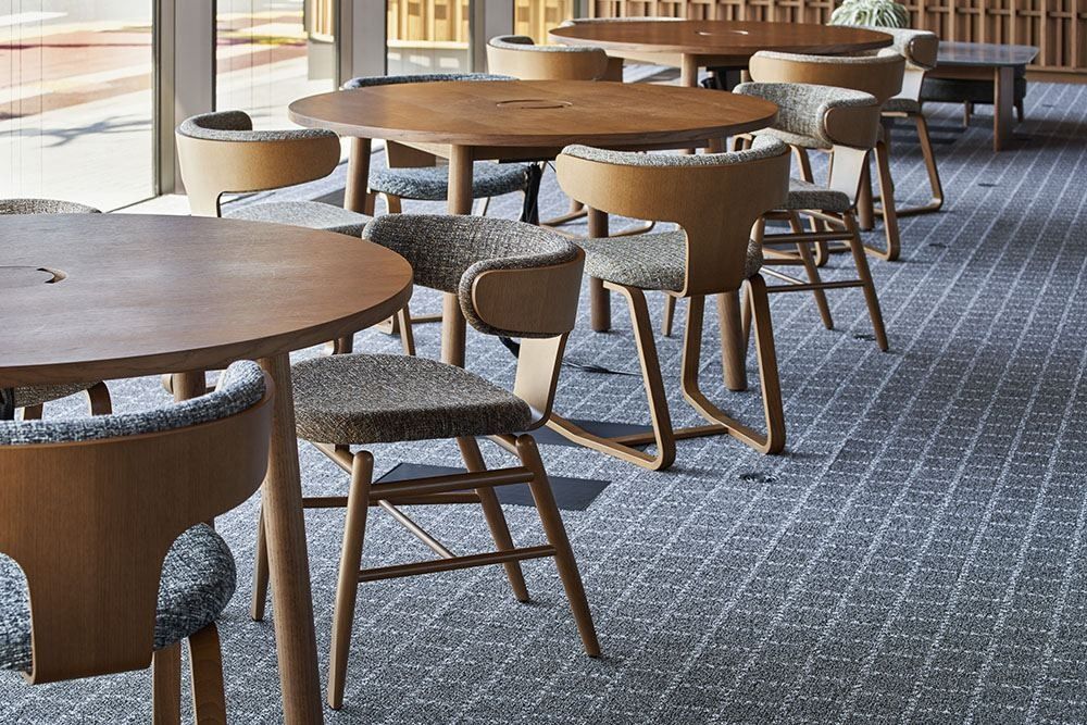 ZOZO: Round wooden tables with curved bentwood chairs on a patterned carpet
