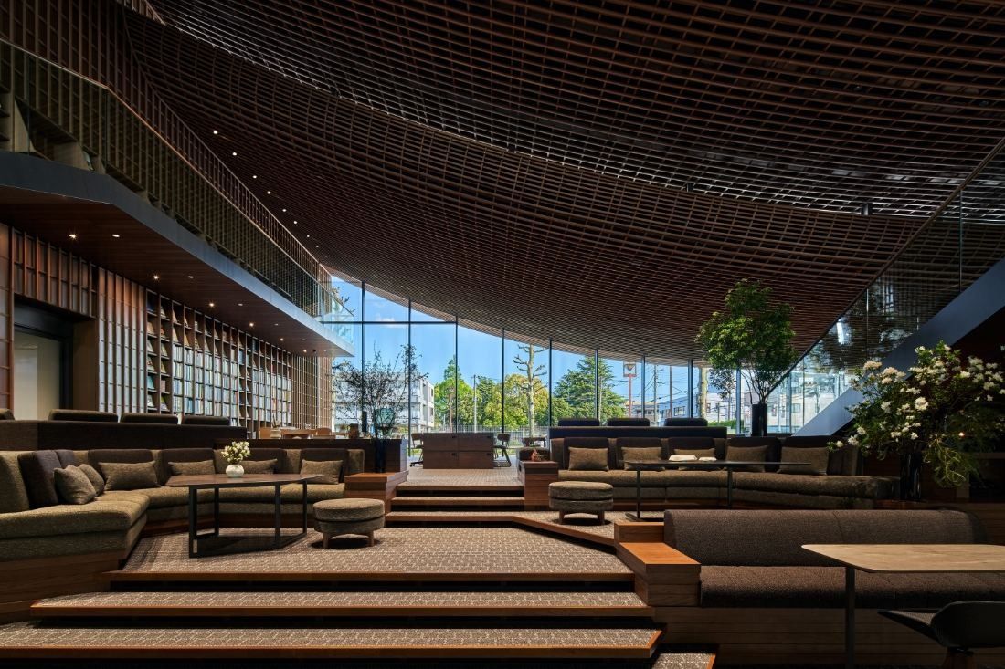 ZOZO: Stepped lounge with sofas under a wooden lattice ceiling and tall windows with trees outside