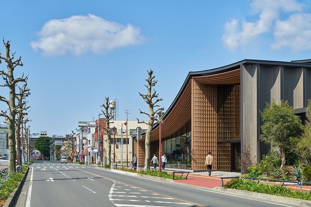 ZOZO: Street lined with bare trees and the timber-clad end of a building with a curved roof