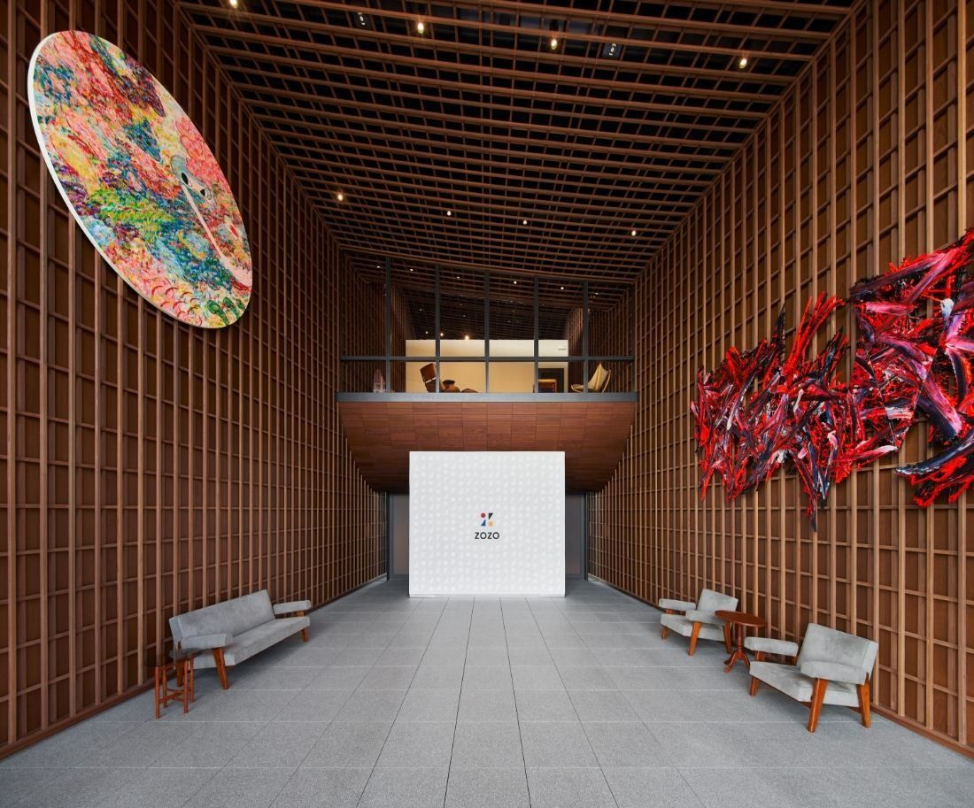 ZOZO: Tall timber-lined entrance hall with artworks on the walls and benches