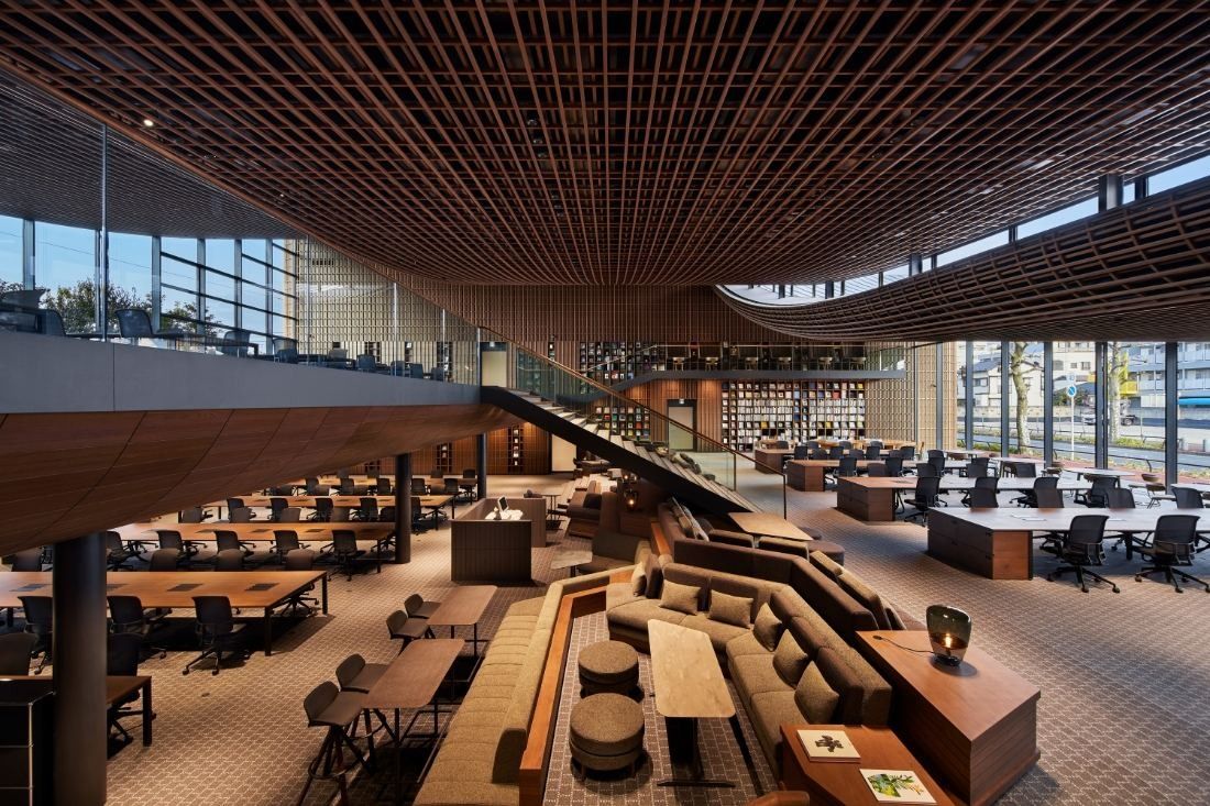 ZOZO: View down over sofas, desks and a staircase under a wooden lattice ceiling