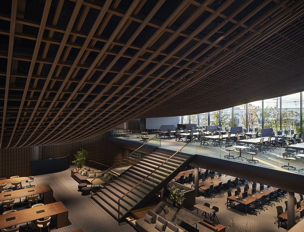 ZOZO: Wide staircase linking two levels of desks under a wooden lattice ceiling