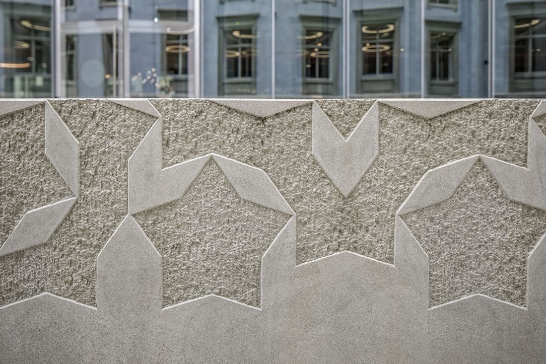 Zurich Insurance Group: Close-up of a stone wall carved with star-shaped relief patterns below a row of windows