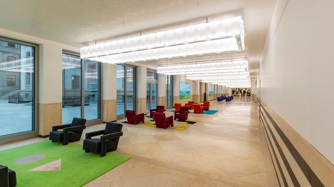 Zurich Insurance Group: Long bright corridor with large windows, red and black armchairs and a strip of green carpet