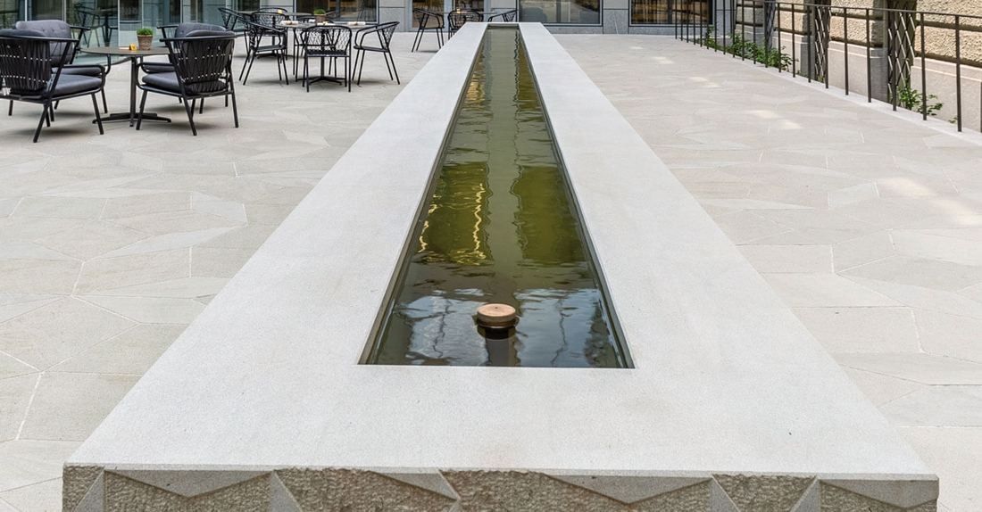Zurich Insurance Group: Long narrow stone basin filled with water stretching across a pale paved courtyard