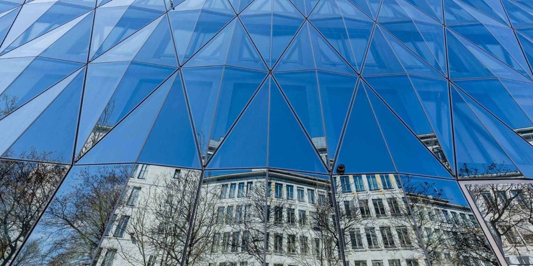 Zurich Insurance Group: Looking up at a facade of triangular glass panels reflecting the sky and neighbouring buildings