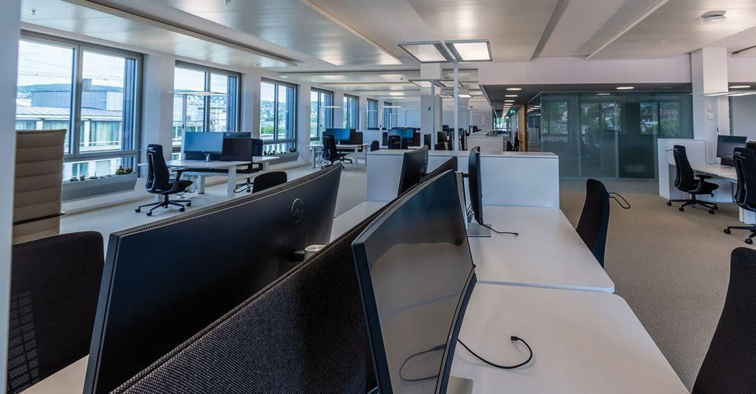 Zurich Insurance Group: Open-plan office with rows of desks and monitors and windows along the side