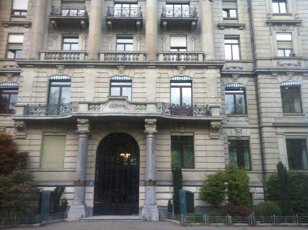 Zurich Insurance Group: Ornate stone facade with columns framing an arched entrance and balconies above