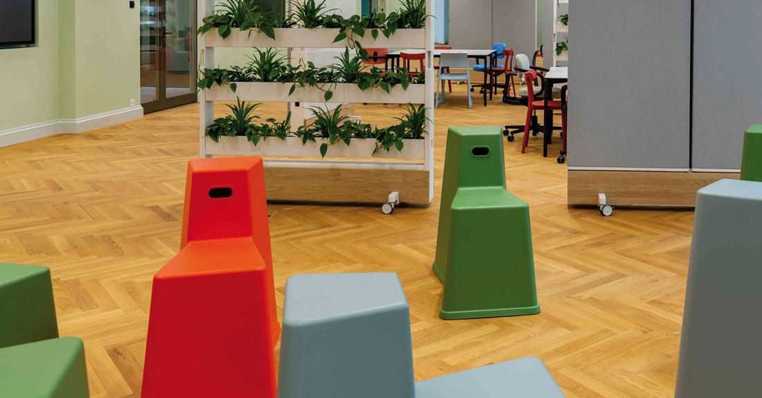 Zurich Insurance Group: Room with colourful stool-like seats on herringbone parquet and a shelf of plants