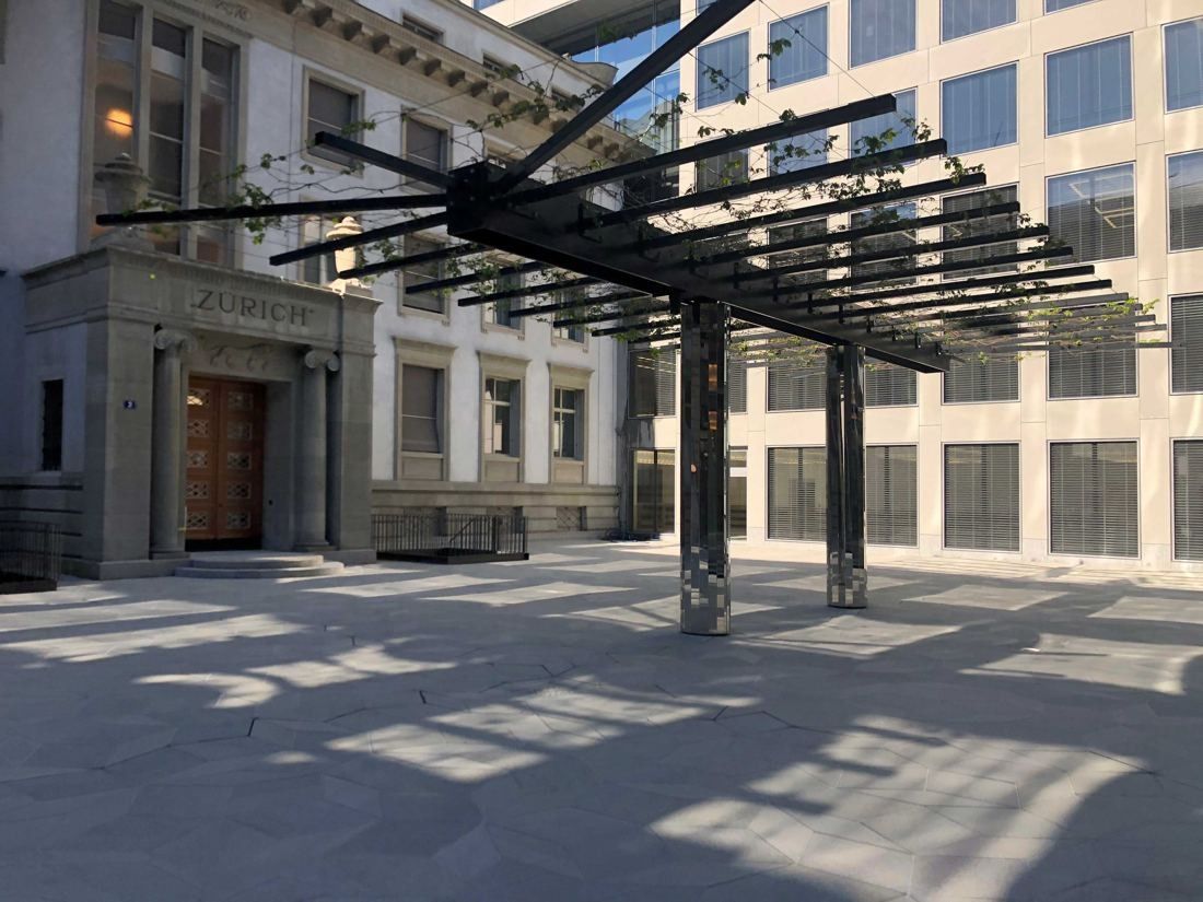 Zurich Insurance Group: Steel canopy structure casting shadows on a paved courtyard in front of a historic entrance