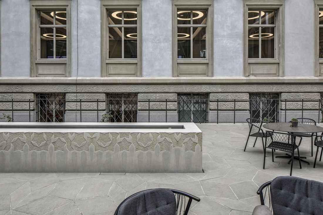 Zurich Insurance Group: Stone trough with relief pattern and outdoor chairs in front of the restored historic facade